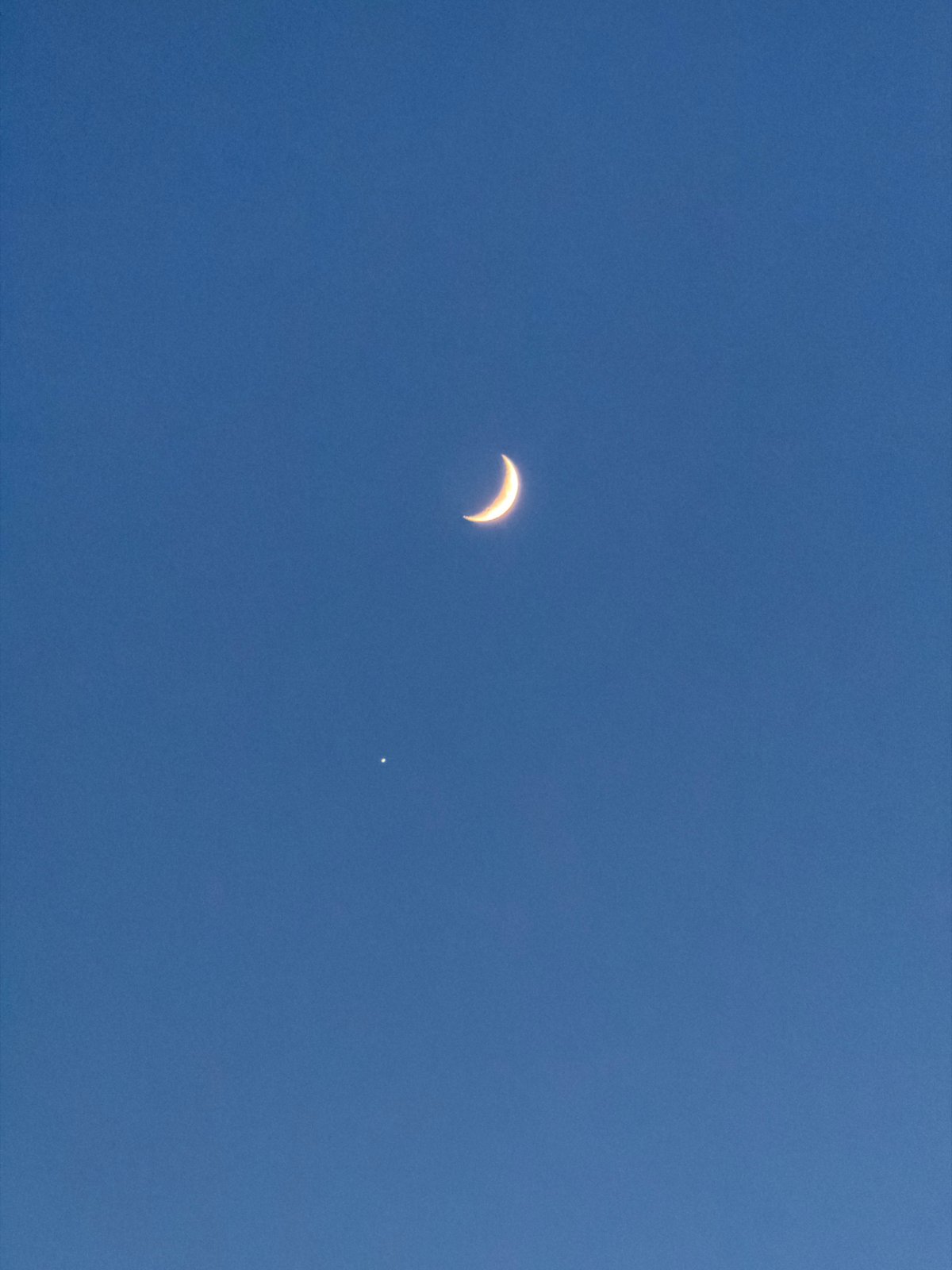 Crescent moon and bright celestial object visible in Krasnoyarsk daytime