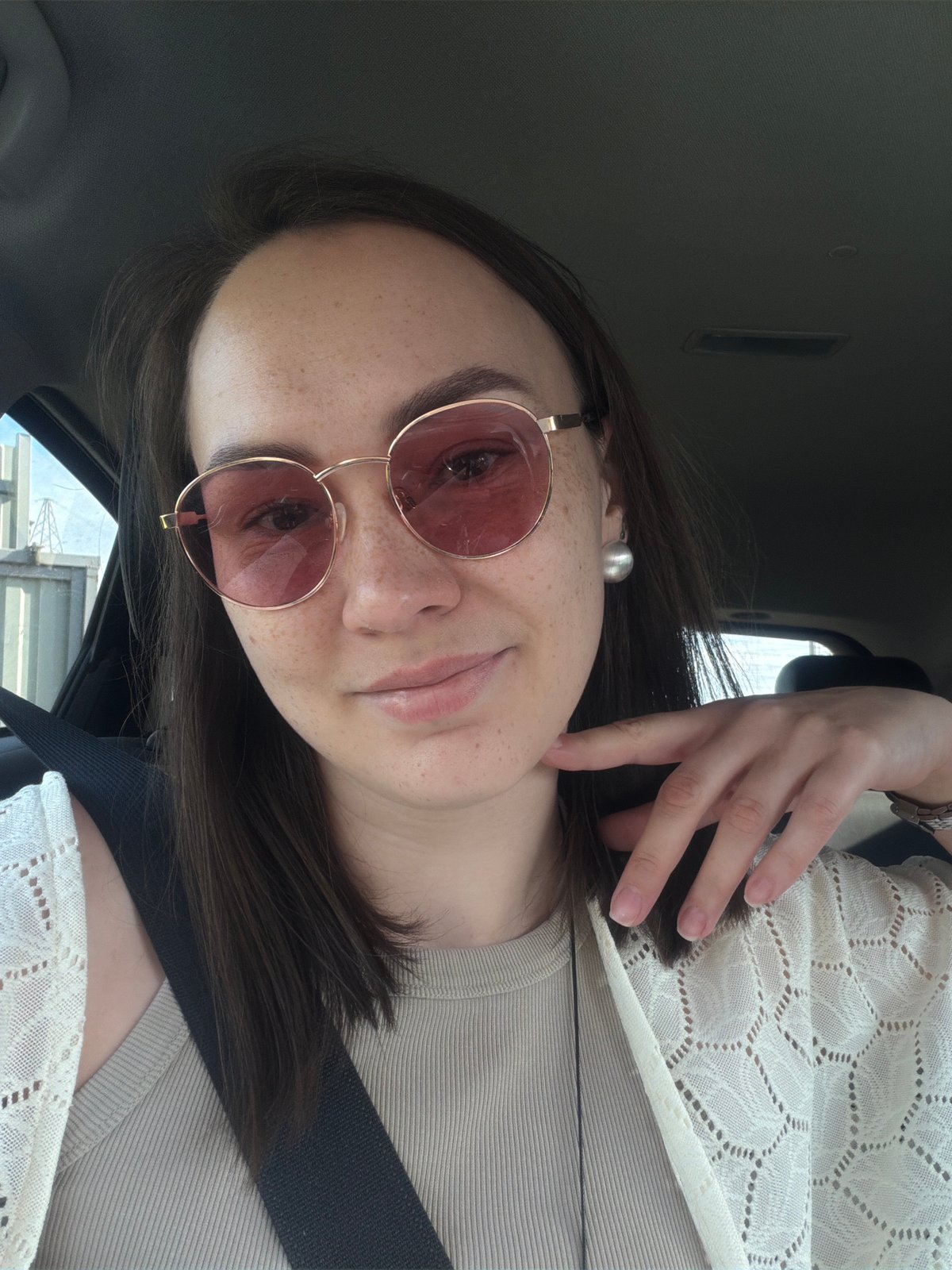 Woman in rose-tinted glasses observed in car passenger seat