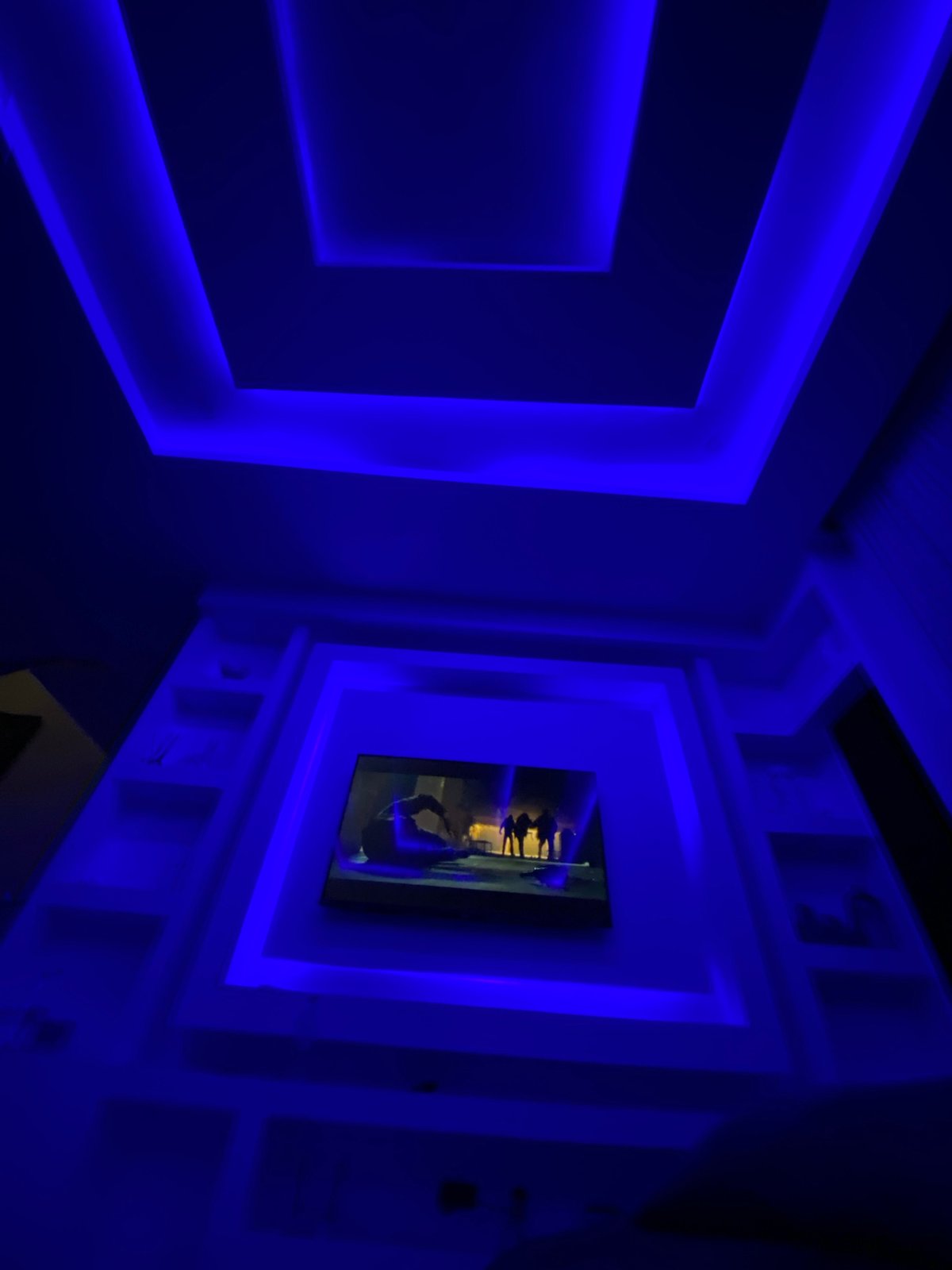Adult plays with toy dinosaurs in blue-lit Lagos apartment
