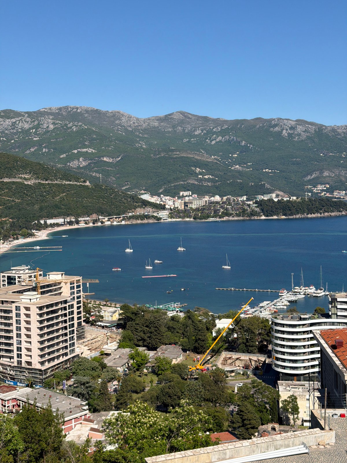 Aerial view captures Budva coastline with boats and construction activity
