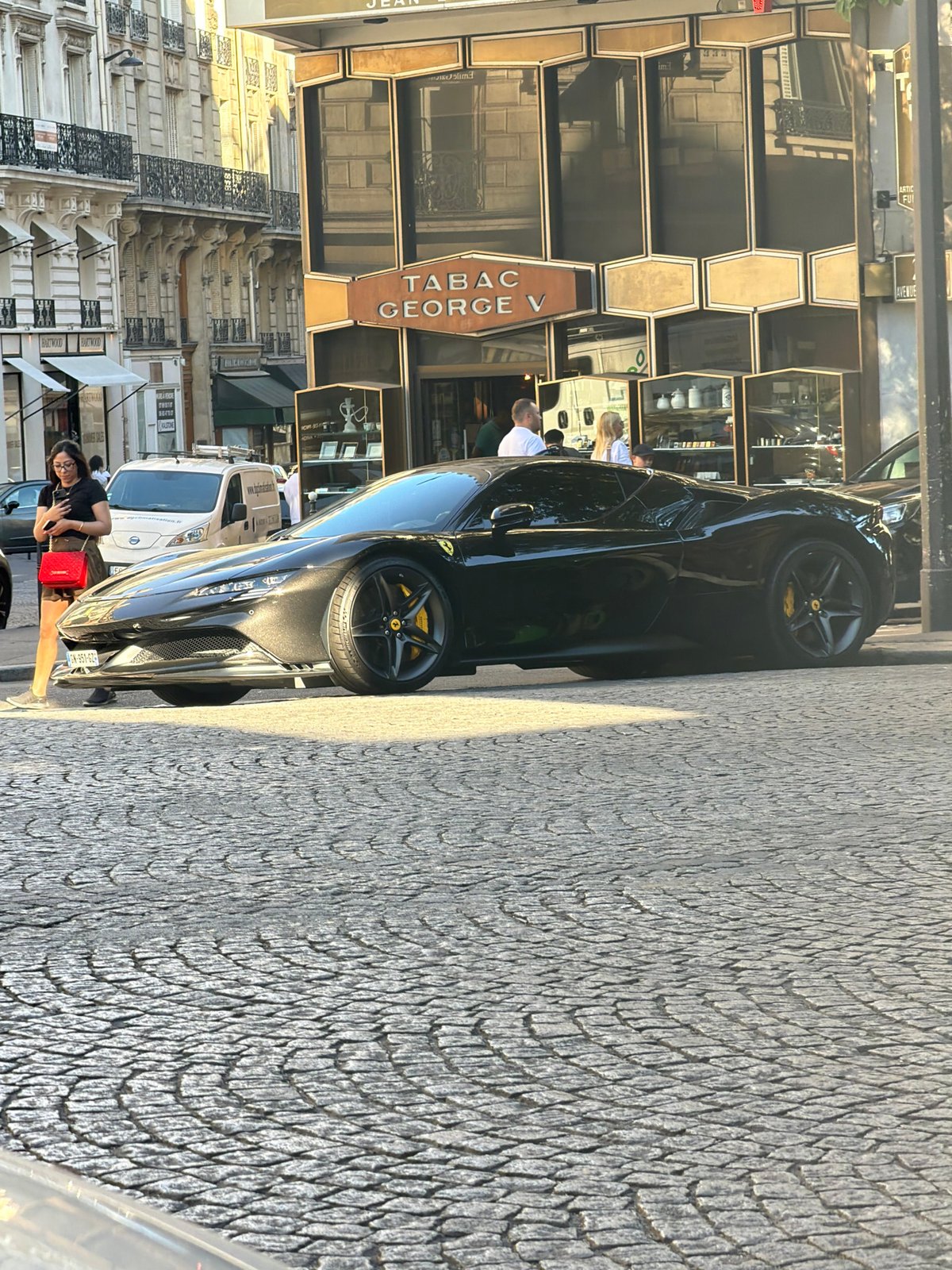 Black Ferrari parked on cobblestone street in historic Paris