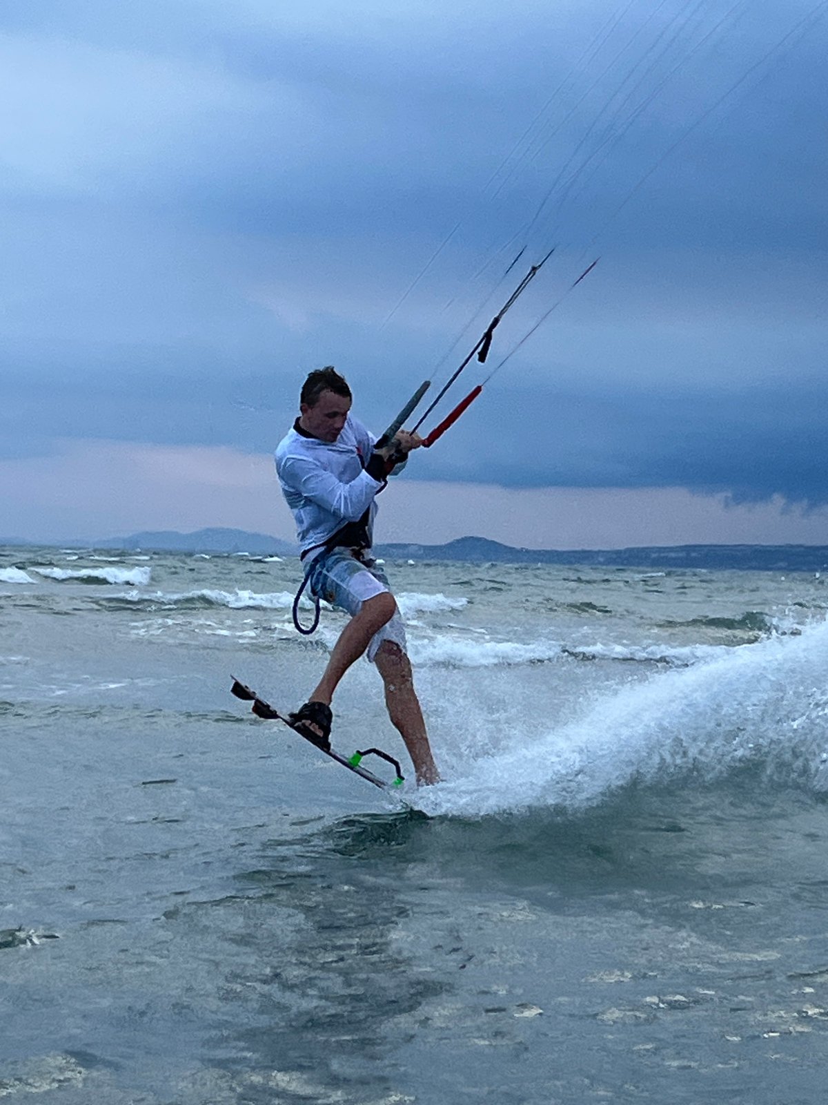 Kitesurfers hit choppy Mũi Né waters under a stormy sky.