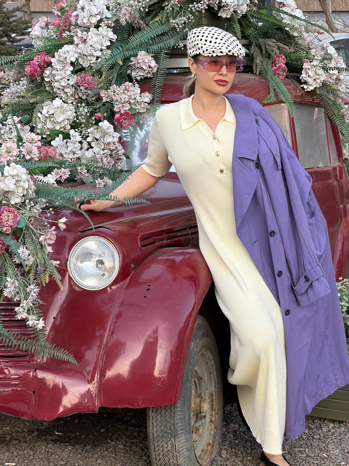 Woman poses on flower-decorated vintage truck at Russian nursery