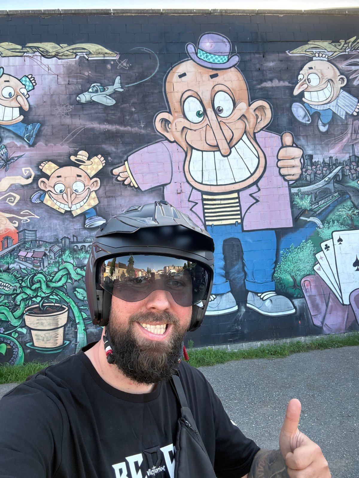 Motorcyclist poses near cartoon mural in Ghent