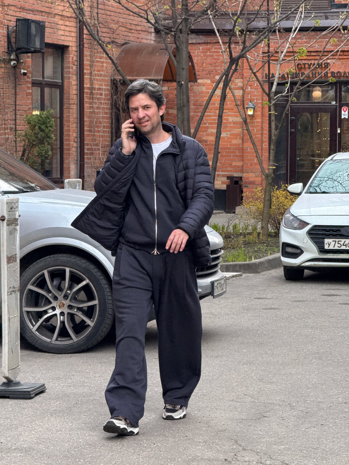 Man in tracksuit stands on Porsche hood in Moscow