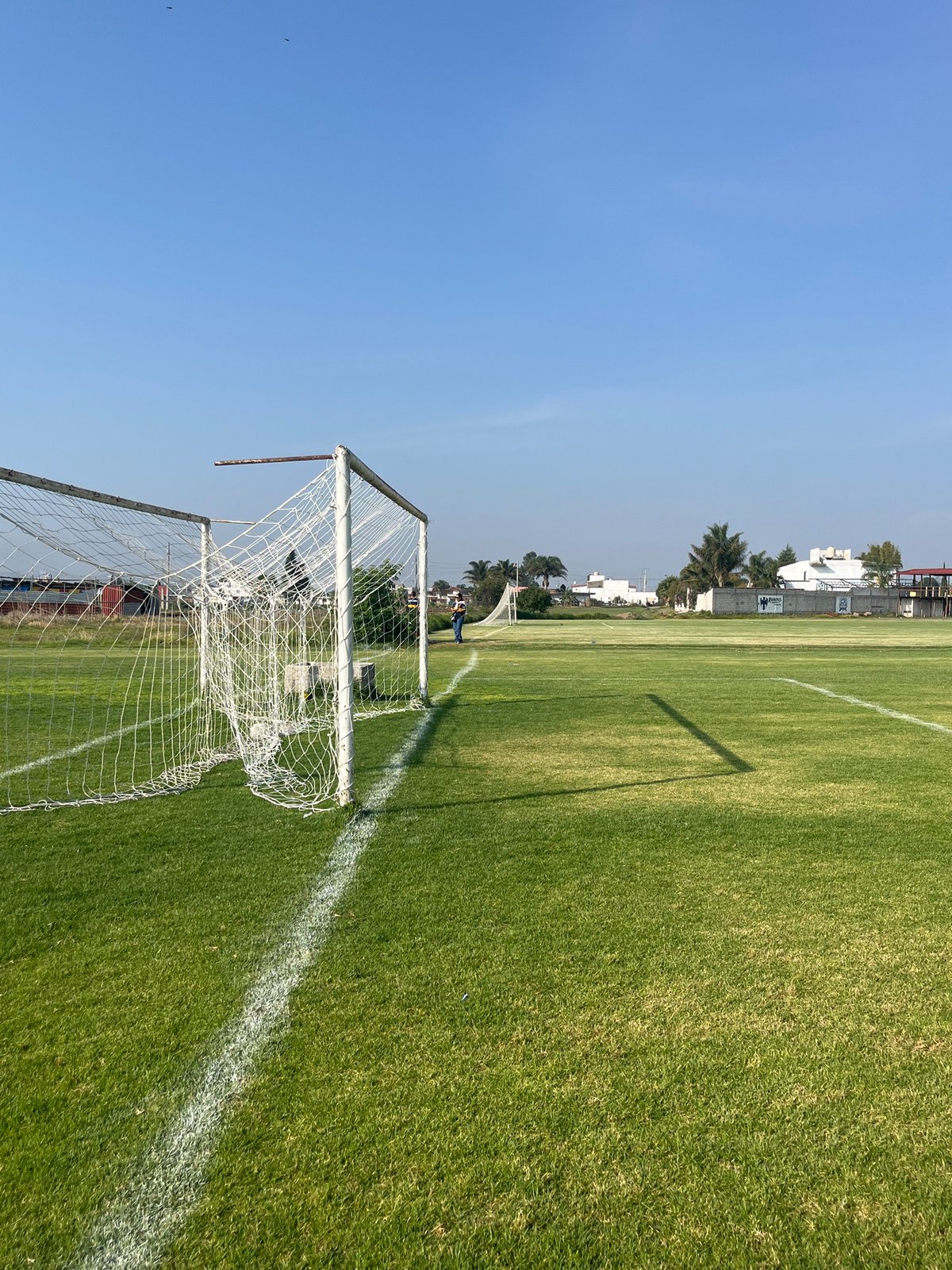 Soccer field observed under clear skies with buildings nearby