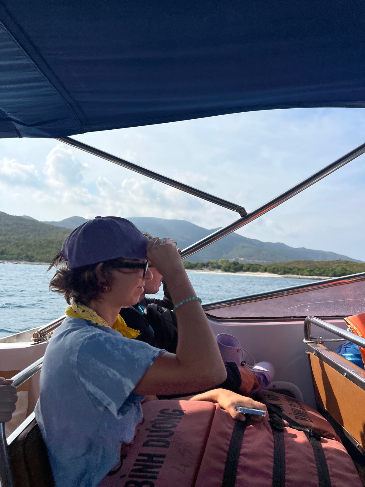 Boat passenger uses phone near orange items in Vietnam