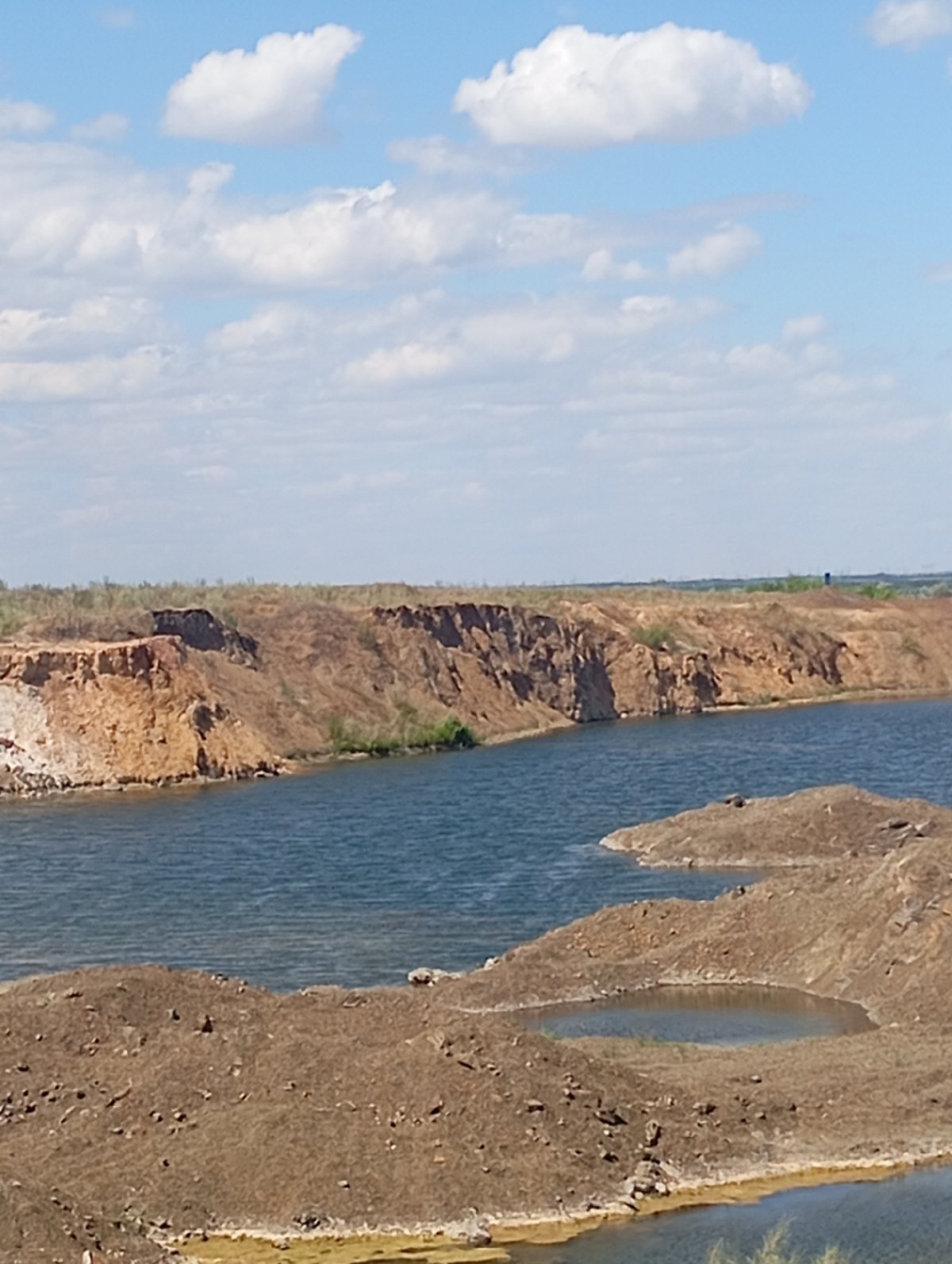 Flooded quarry with red cliffs and still blue water