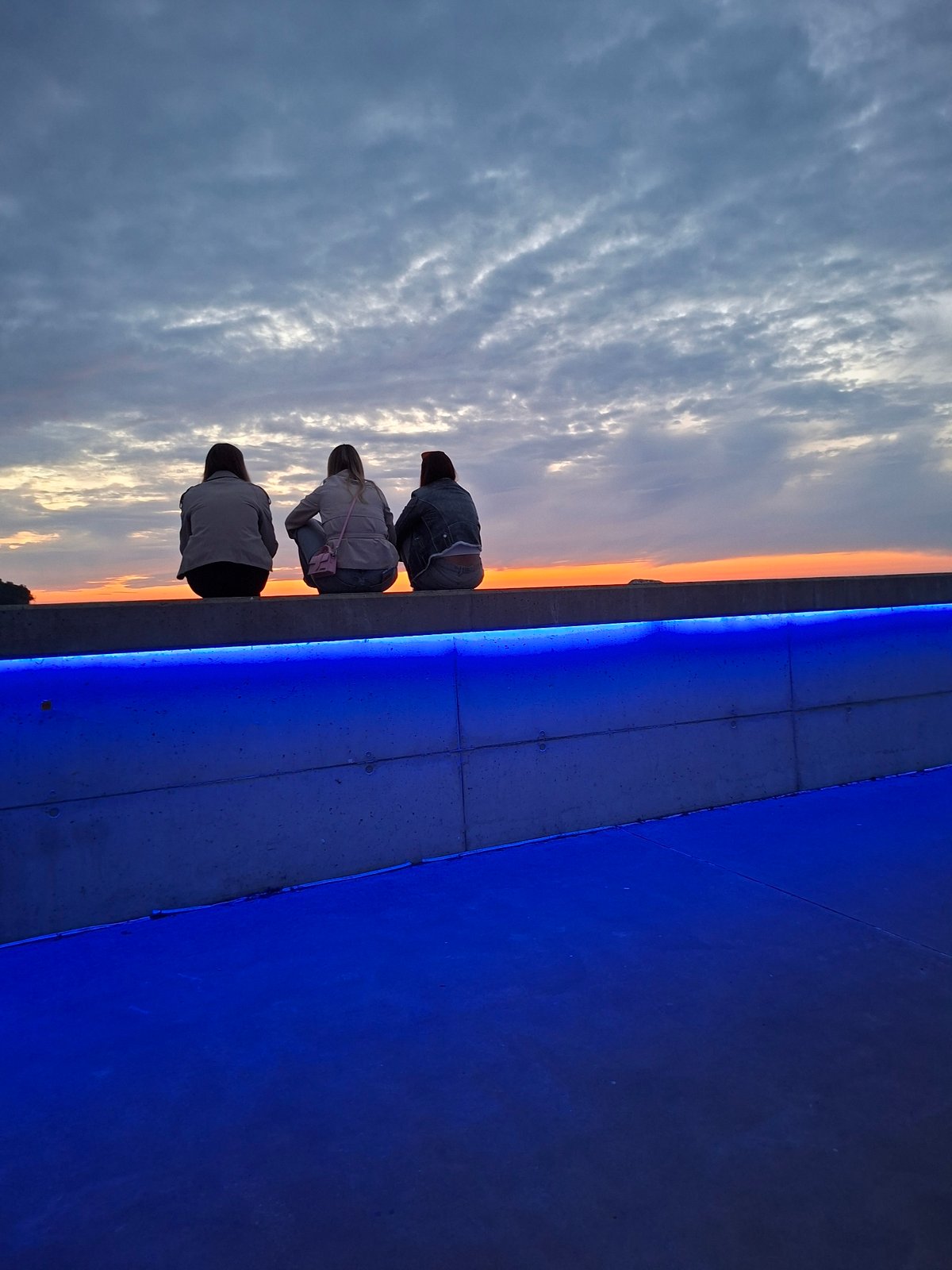 Sunset watchers gather at illuminated Tallinn waterfront promenade