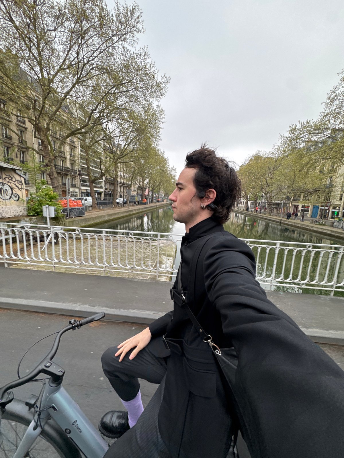 Cyclist pauses on Paris bridge during morning hours