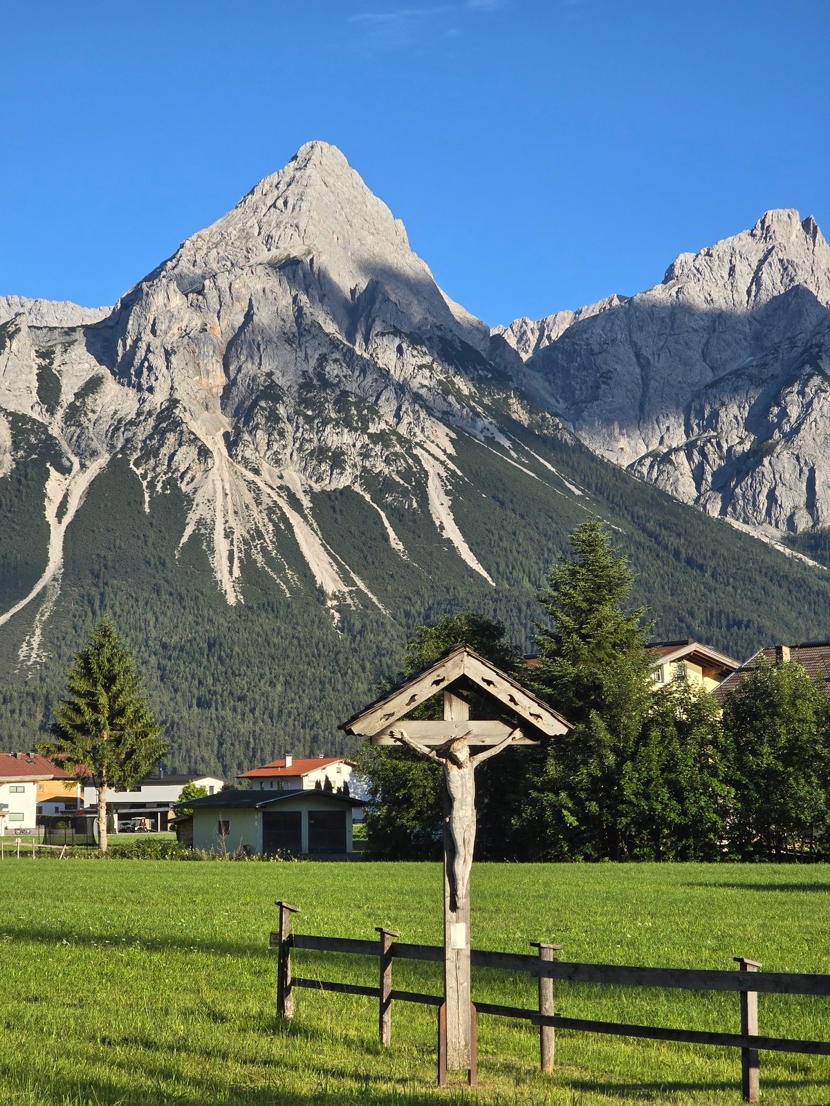 Wooden cross and alpine peaks on a clear day in Lermoos