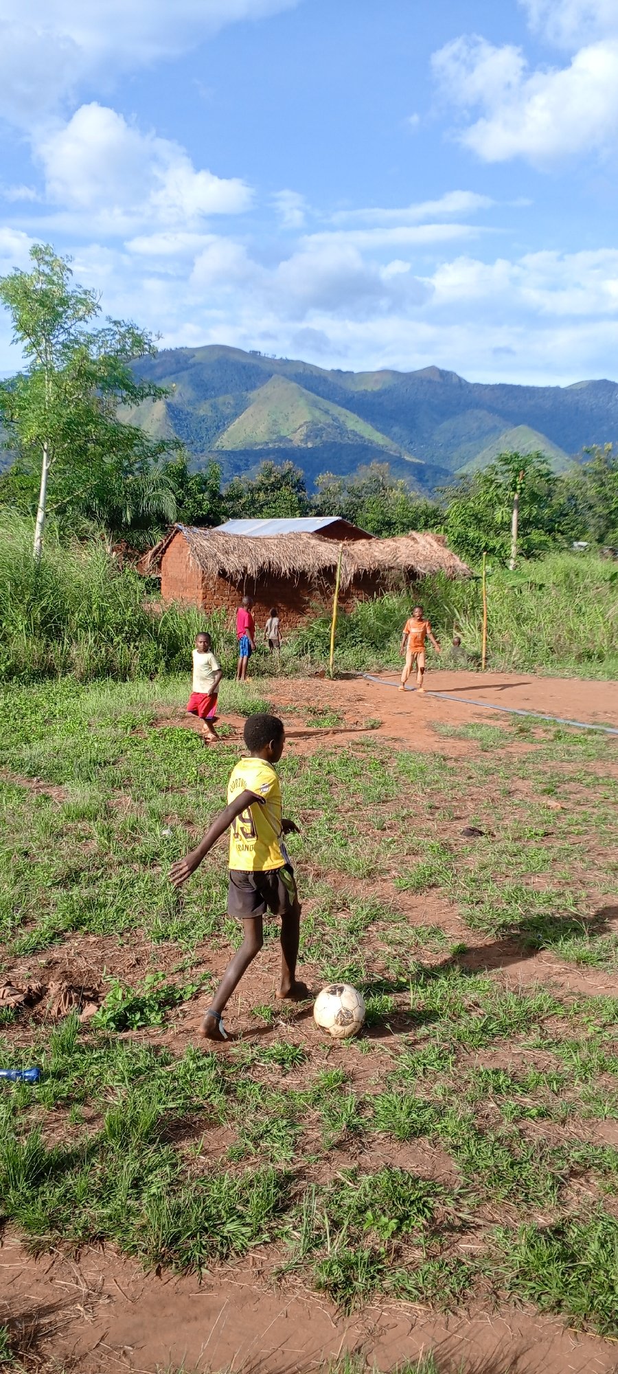 Children play soccer on dirt field in rural Congo