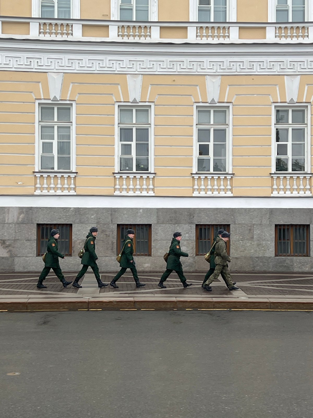 Soldiers march in formation near striped building in Saint Petersburg