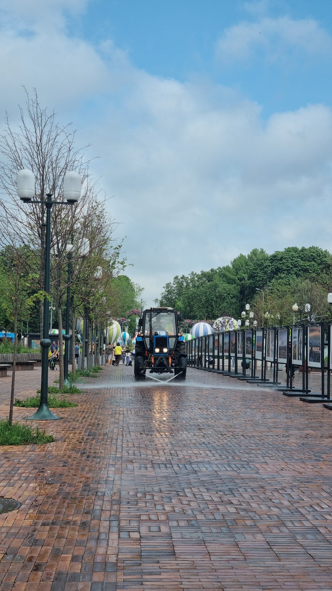 Moscow park morning: metro monument, wet brick paths, city backdrop