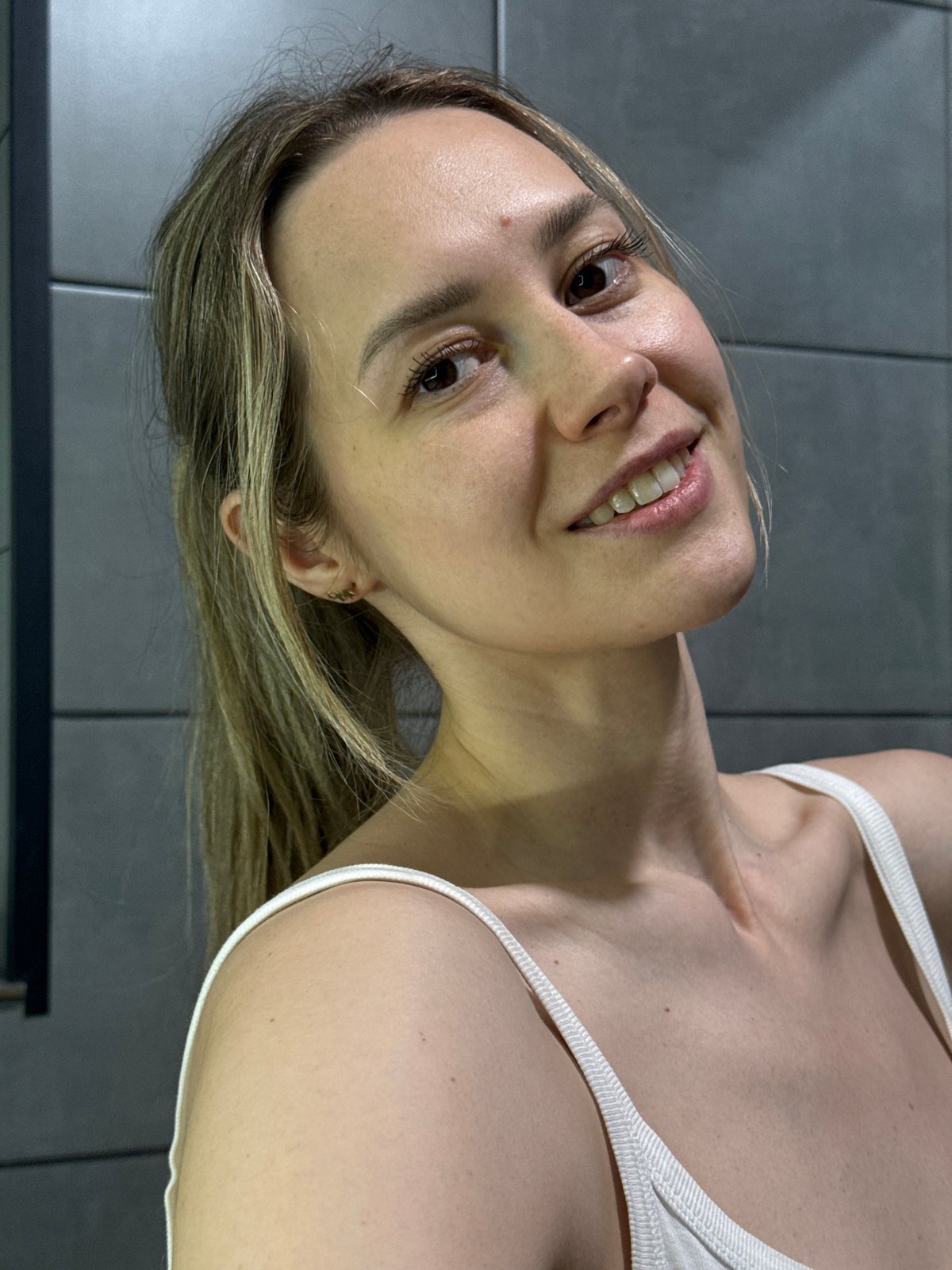 Woman photographed smiling in bathroom setting in Chaikovsky, Russia