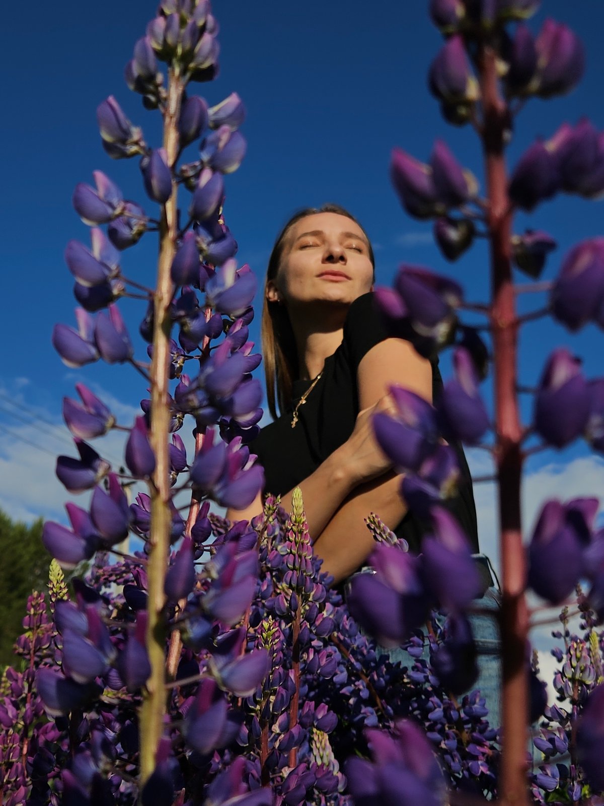 Woman poses in lupine flower field near Russian Orthodox church