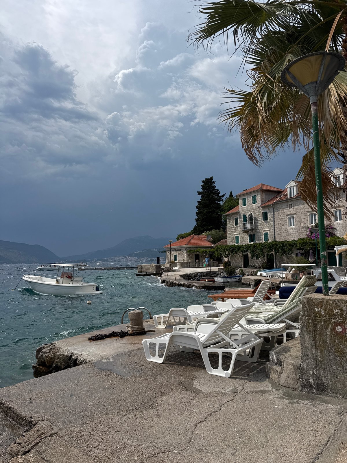 Choppy waterfront, moored boats, and stone buildings midday