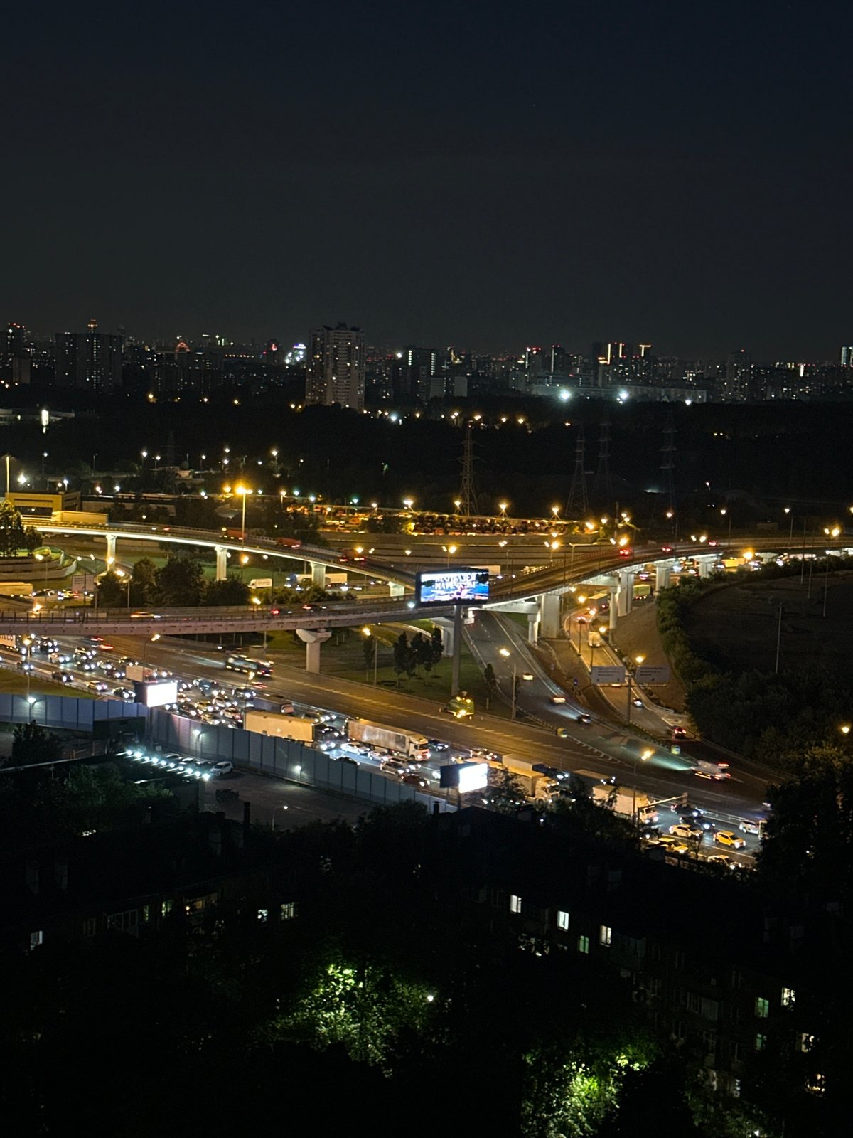 Orange moon rises over Khimki's glowing highway interchange at night