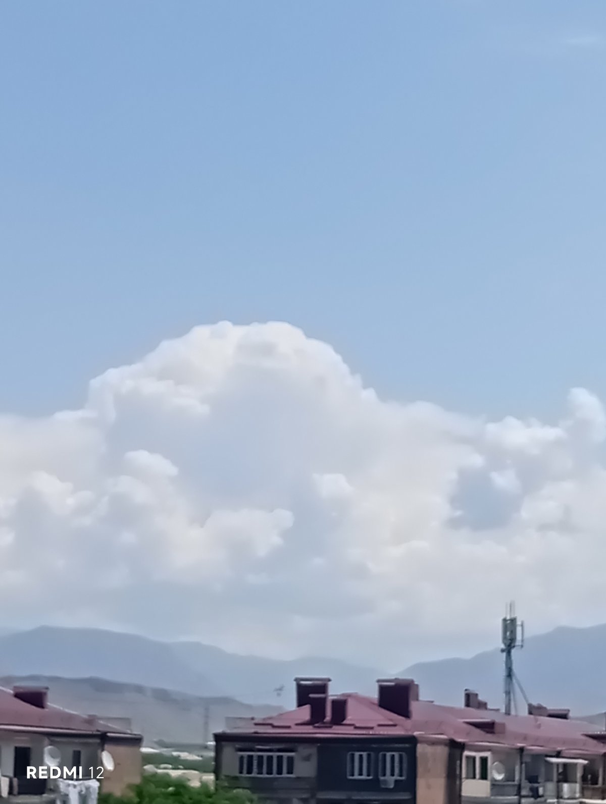 Suburban red-roofed buildings observed under blue sky with clouds