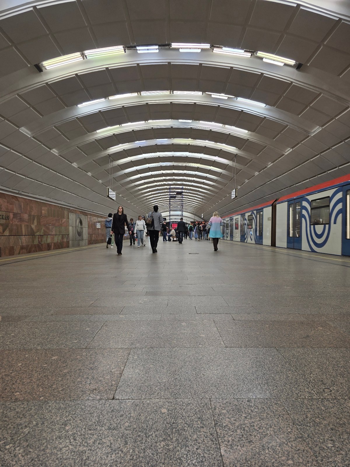 Subway train arrives at station platform displaying Cyrillic destination