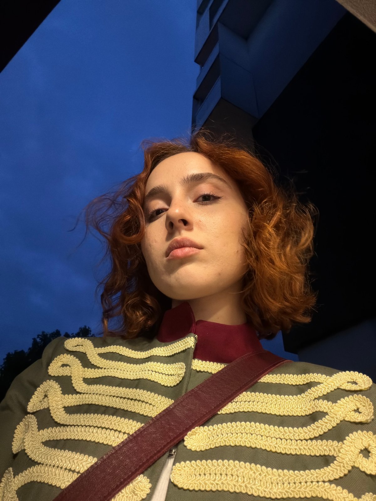 Woman takes selfies in Strasbourg hallway wearing military-style jacket