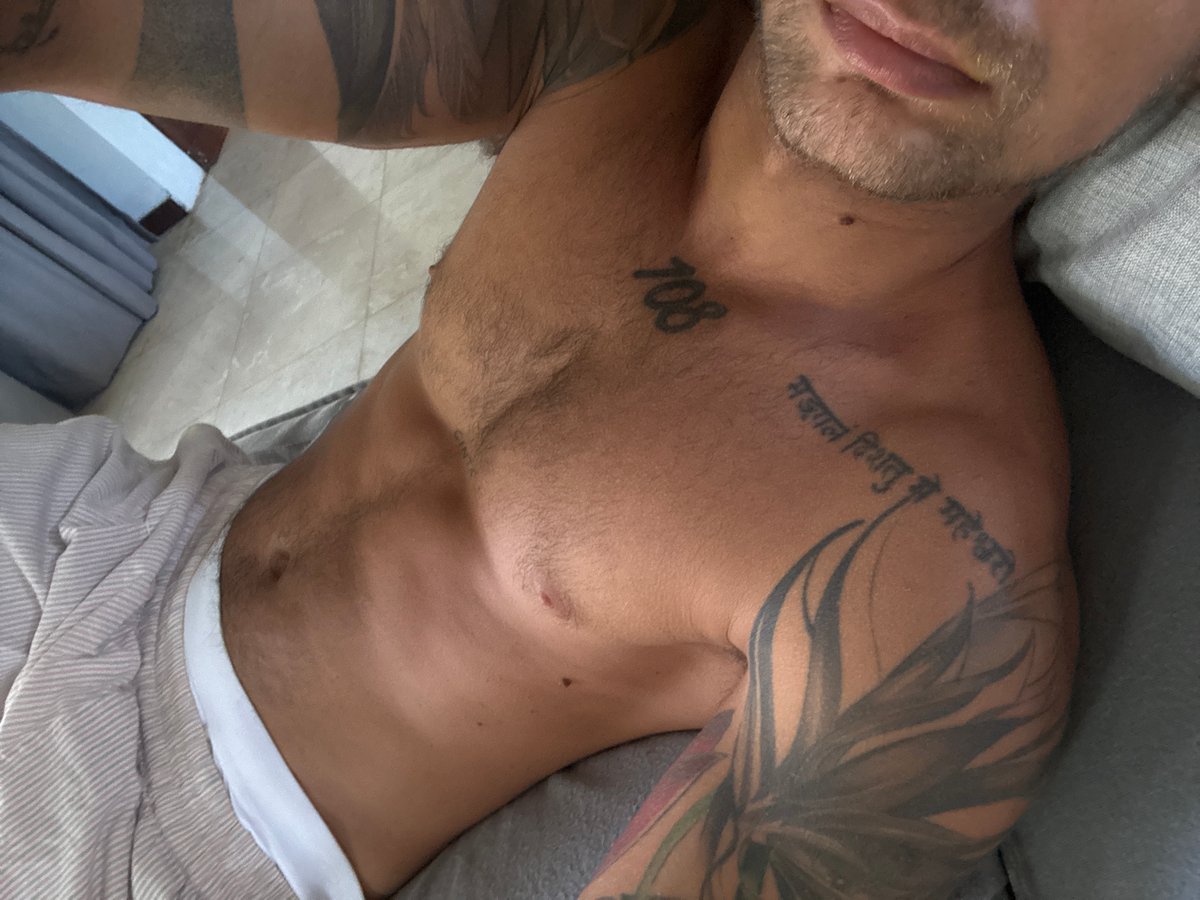 Shirtless rest on a gray couch, tattoos visible, Kuta Selatan