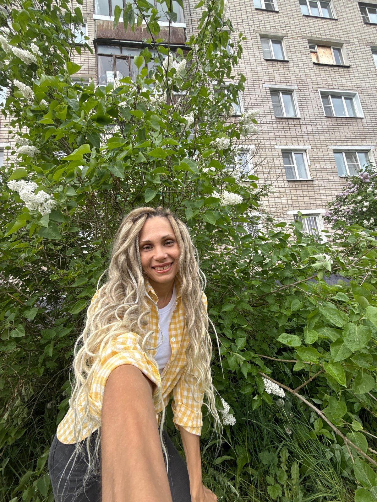 Woman poses among lilac flowers in Russian village morning