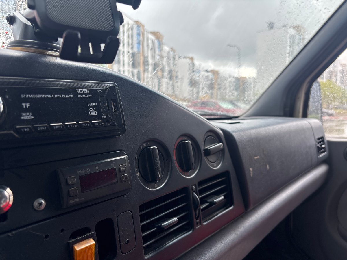 Rainy city drive past modern buildings and a parked delivery van