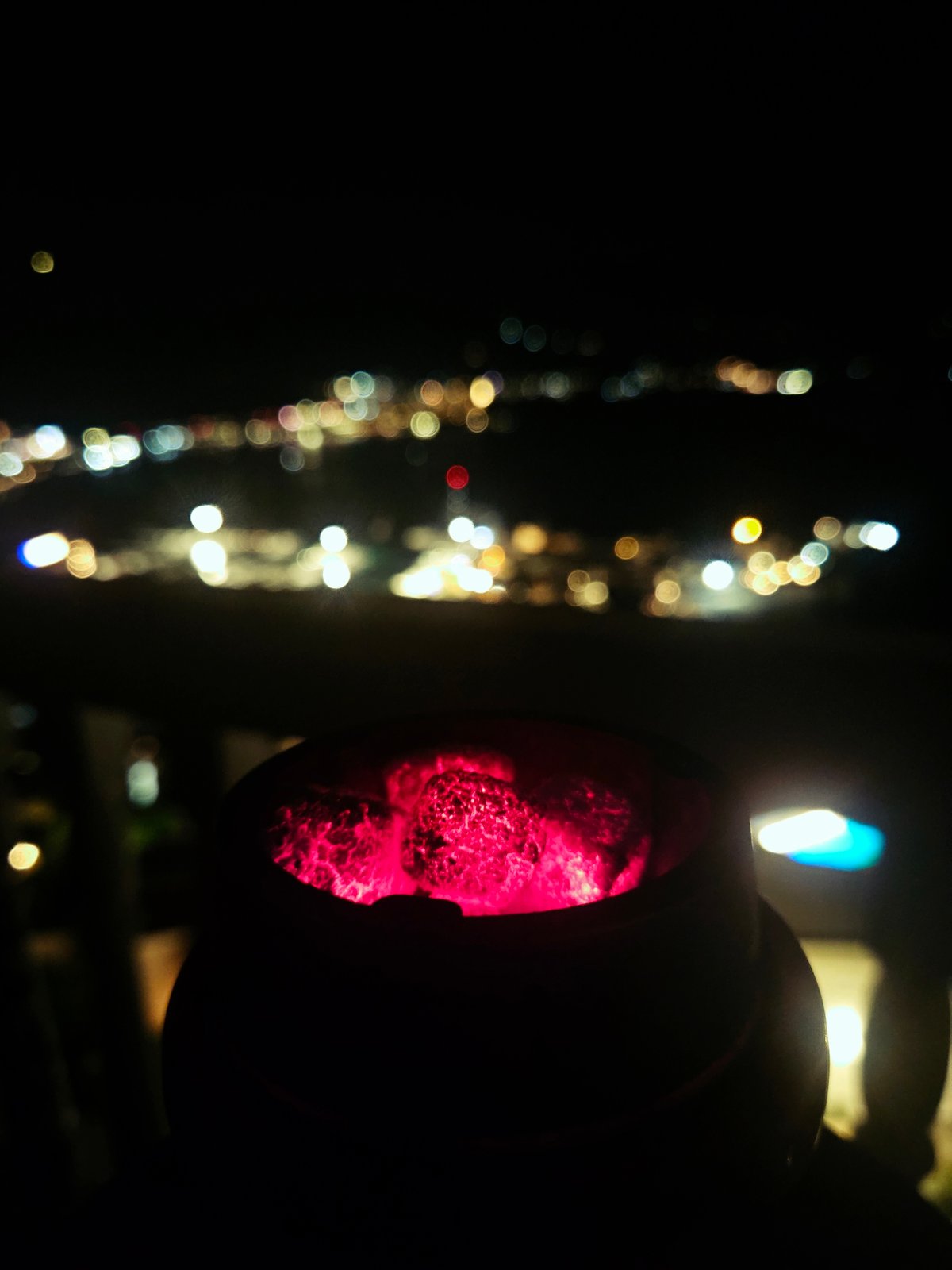 Evening hookah session on city balcony overlooking waterfront lights
