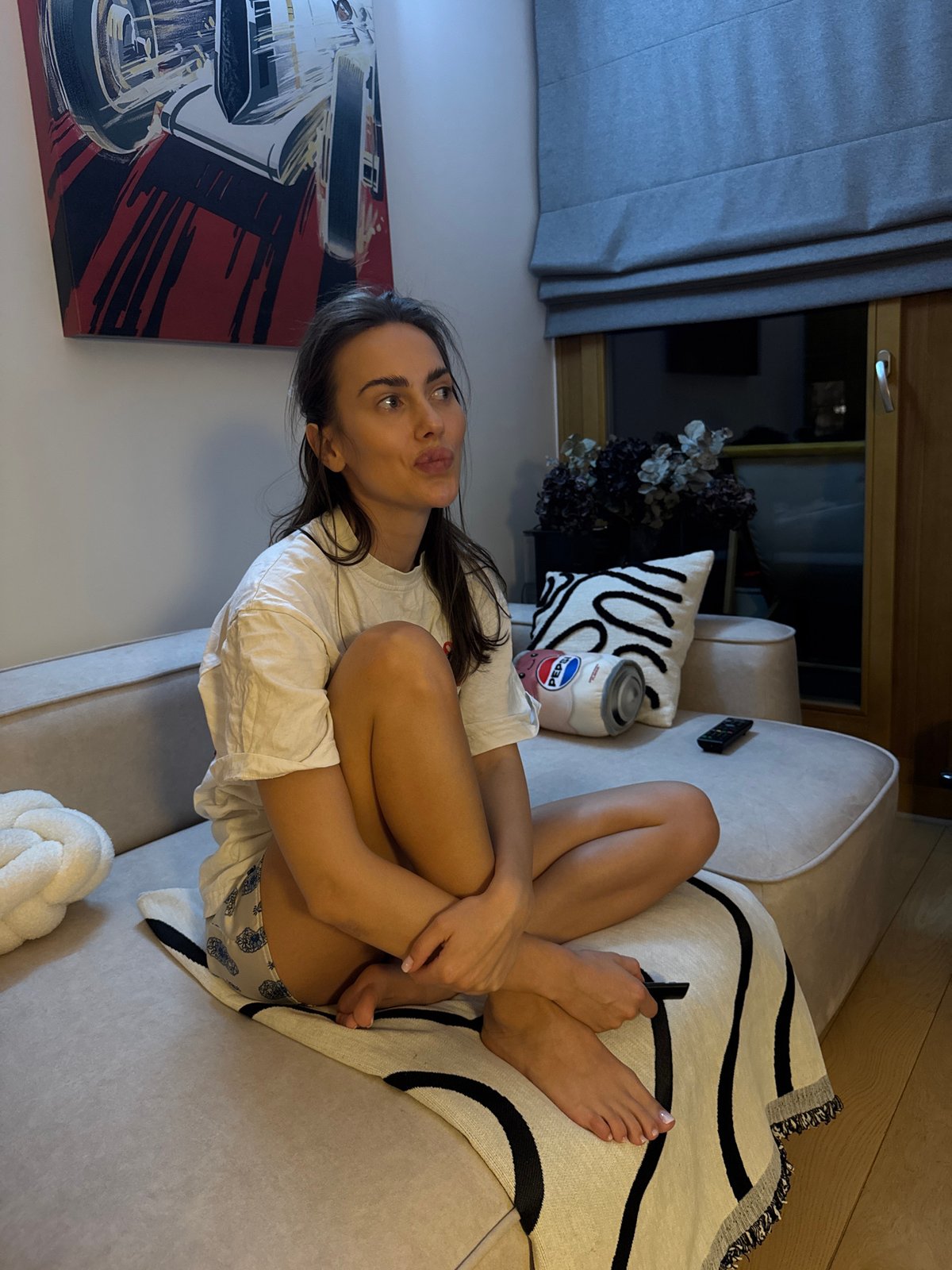 Woman relaxes on couch with drink and phone