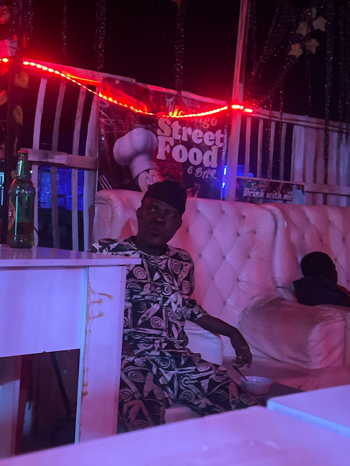 Late-night street food spot glowing under red LEDs in Nigeria
