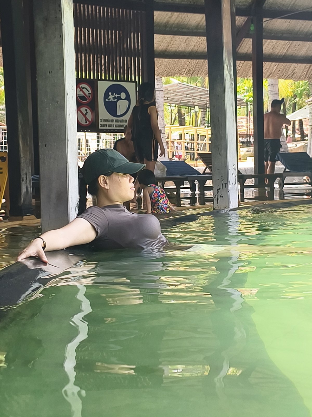 Woman relaxes in green-tinted pool or hot spring