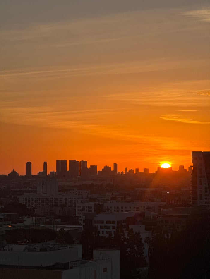 Orange sunset illuminates Los Angeles skyline with dramatic shadows