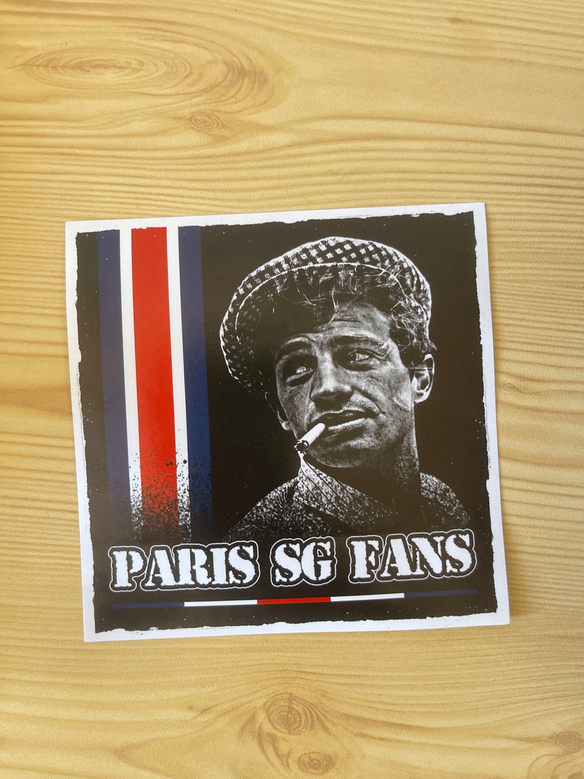 Stickers and a coaster on a wooden surface in Paris