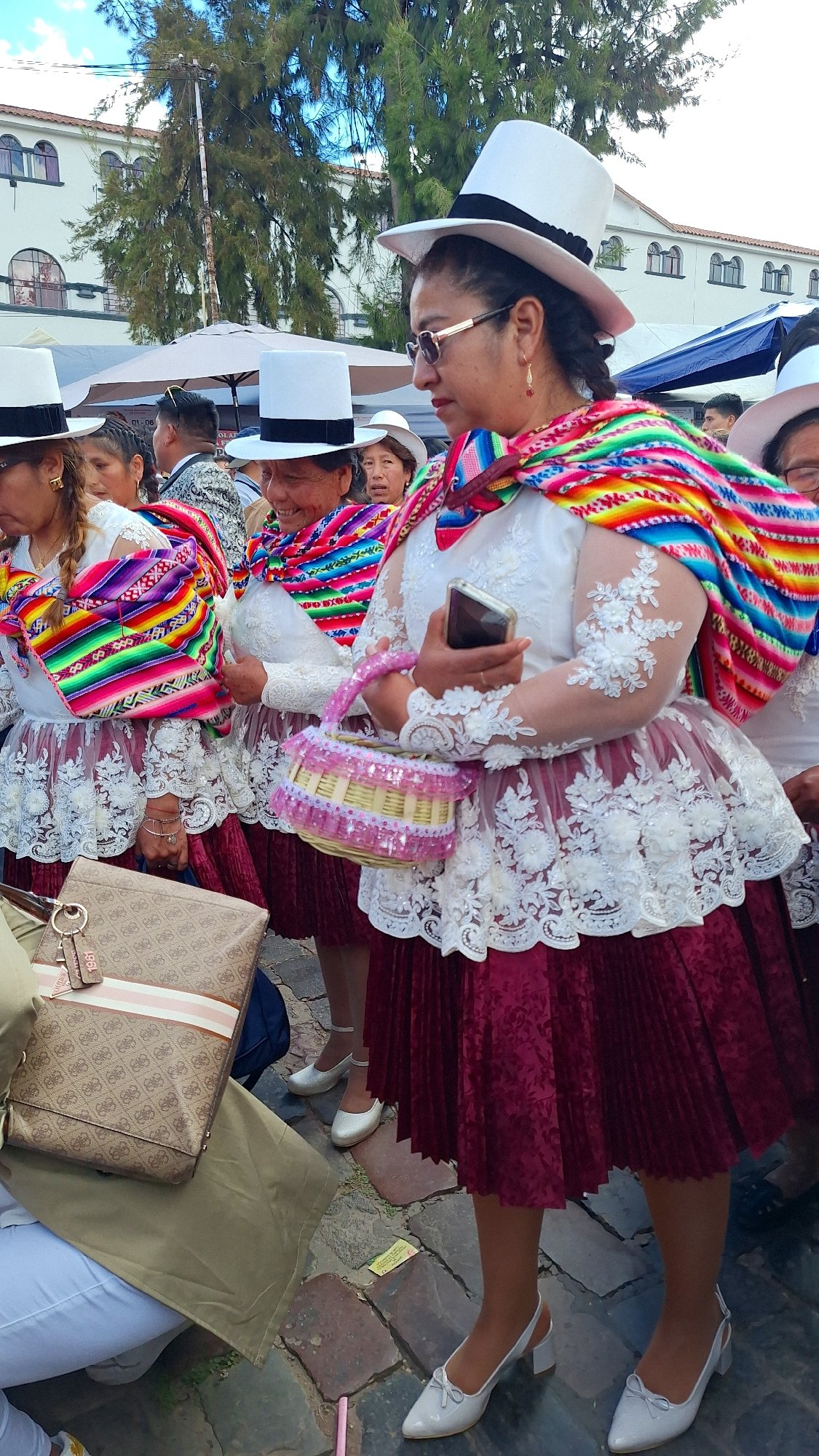 Women in traditional dress gather outdoors in daytime gathering