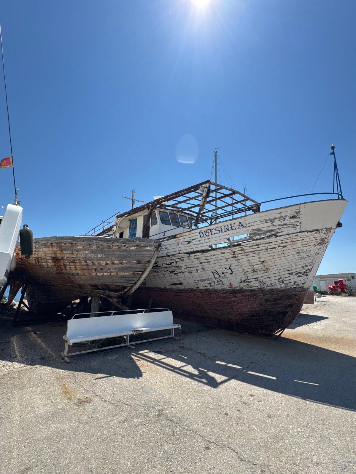 Weathered wooden boat mid-restoration on dry land in Bar
