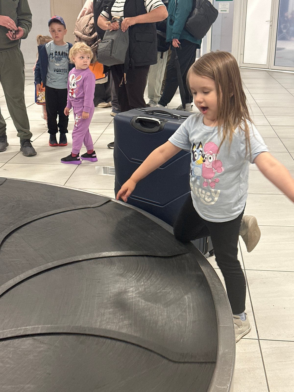 Child sits on suitcase at Russian airport baggage claim
