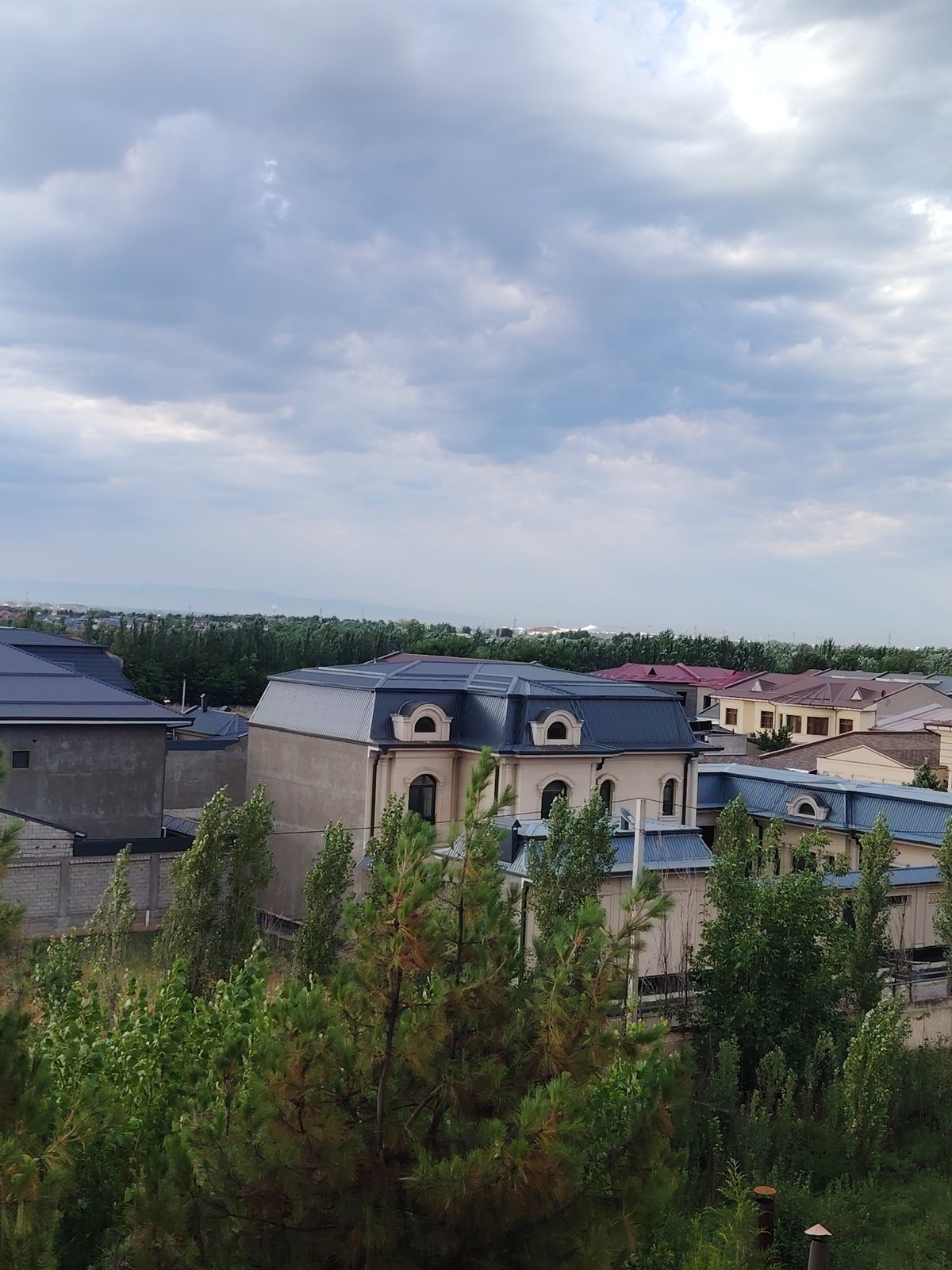 Cloudy day over tree-lined residential Argin, mountains in the background