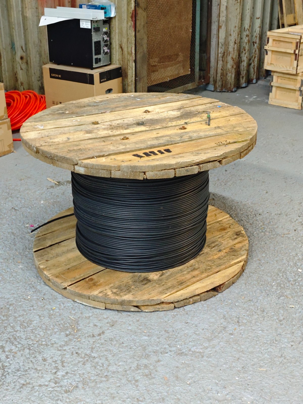 Industrial workspace with cable spools, storage crates, and electrical components