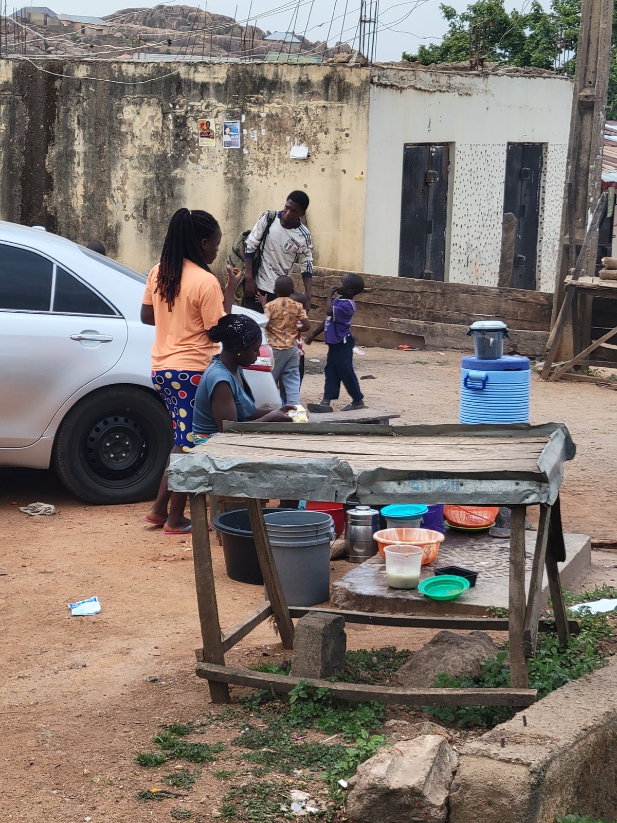 Daily life unfolds around water stand, children play in Jos streets