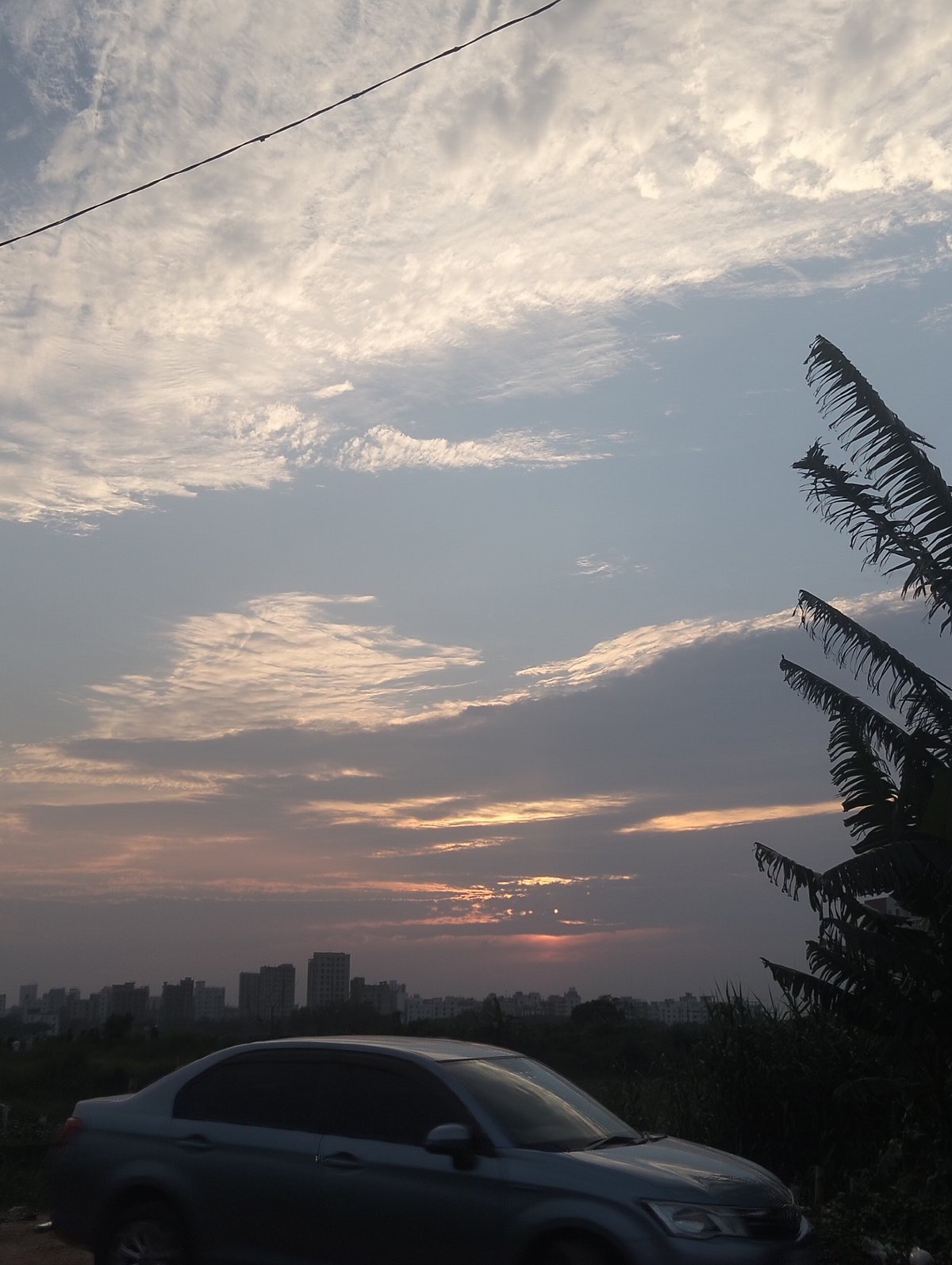 Gray sedan parked in Dhaka lot during sunset