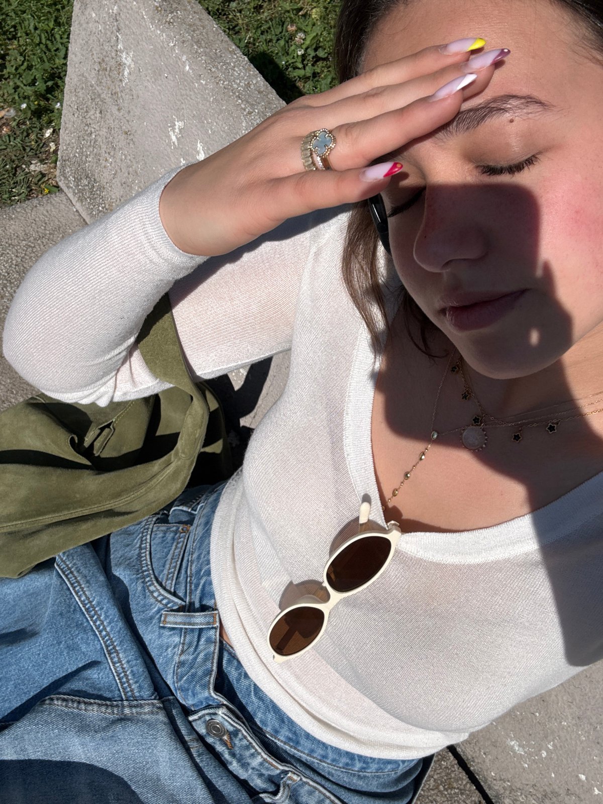 Woman rests in Milan park wearing denim and jewelry