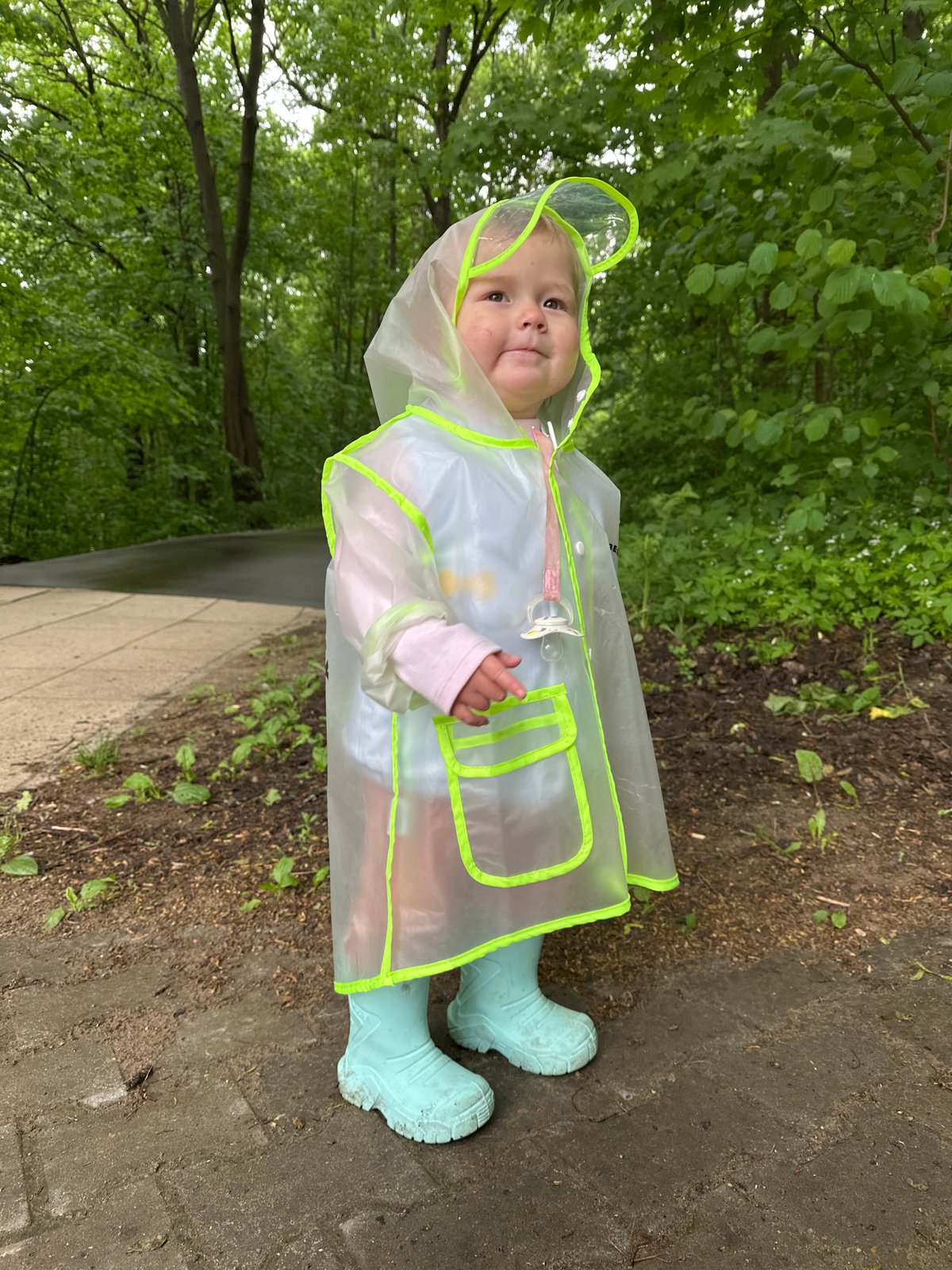 Child in frog raincoat plays in puddles at Nizhny Novgorod park