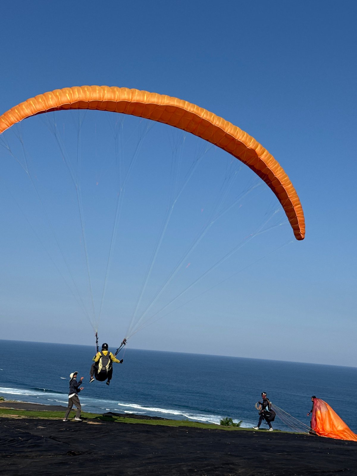 Paragliders soar over Kuta Selatan as tourists capture aerial display