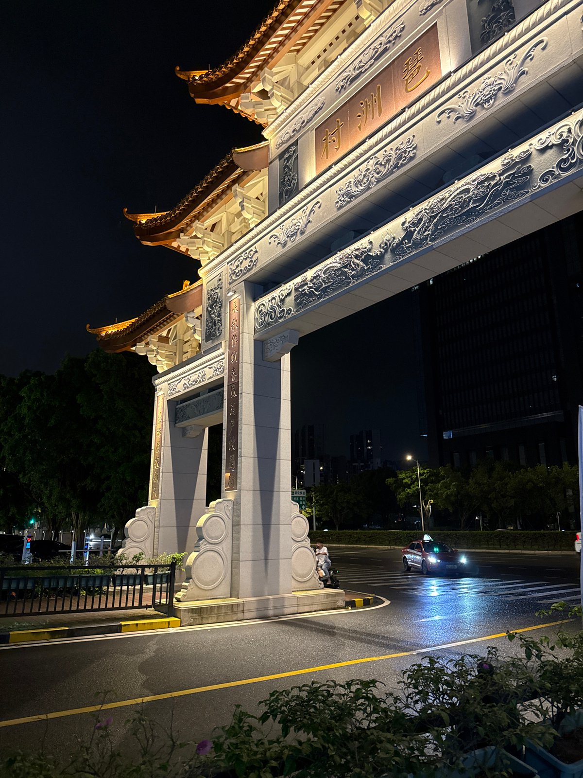 Rainy night in Haizhu: lit archway, wet streets, city in motion