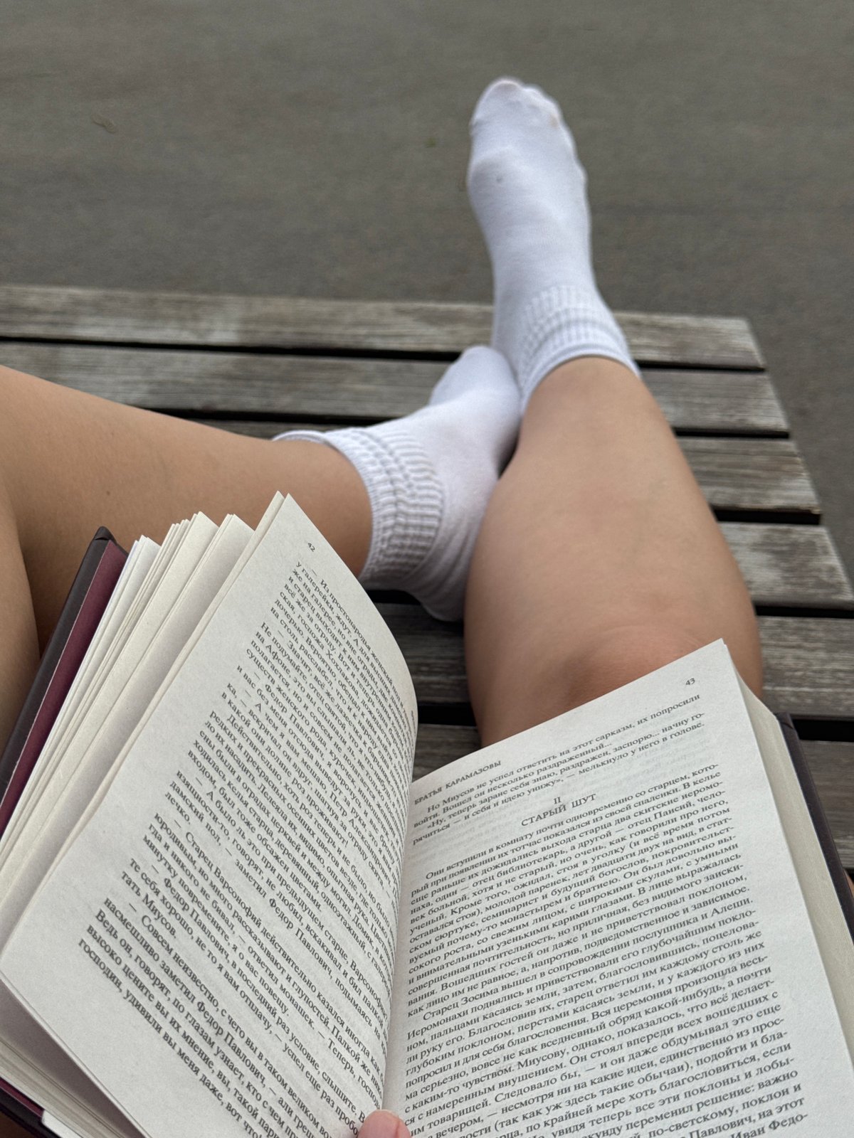 Person reads Russian book on bench by Volga River