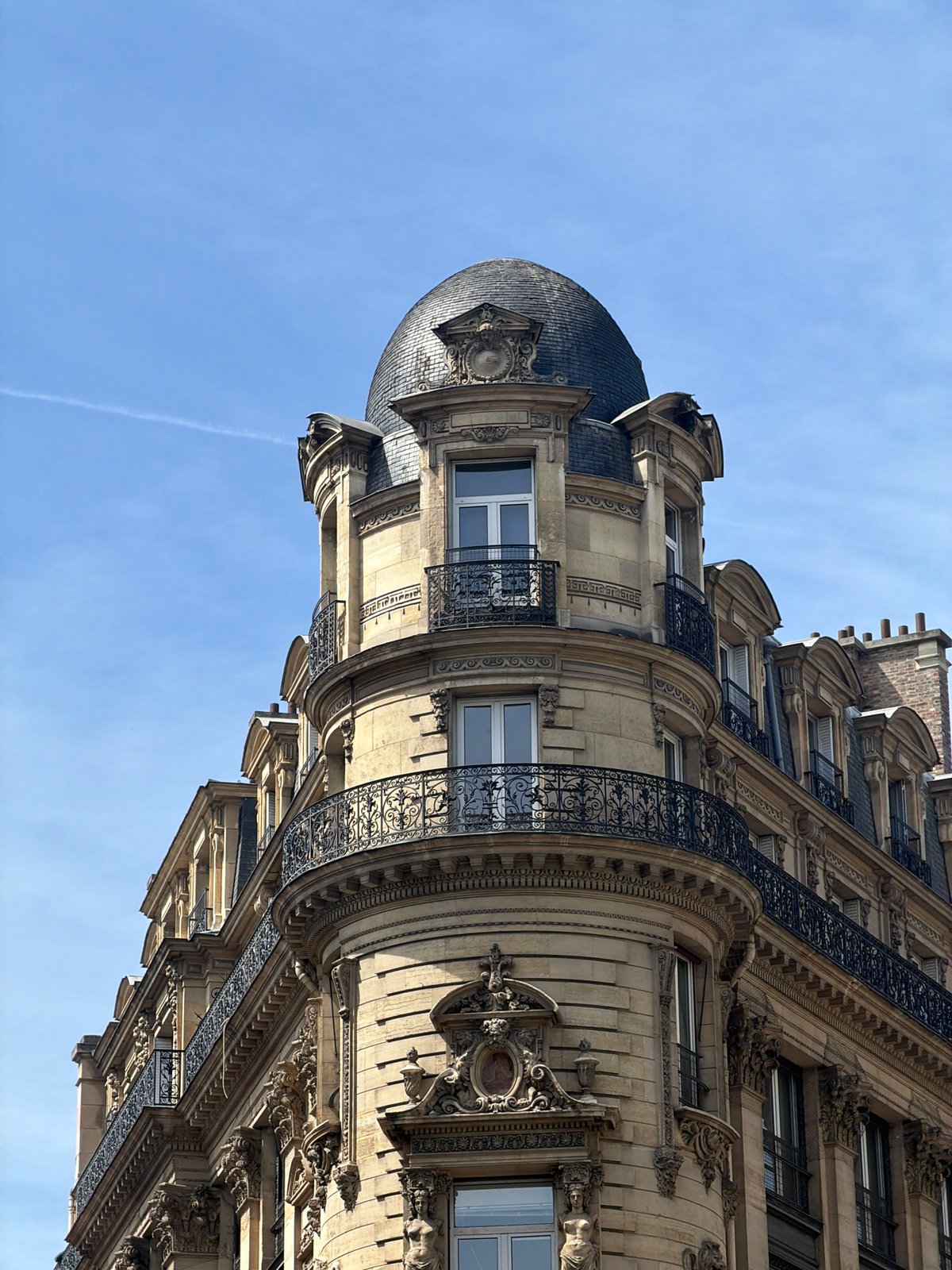 Tourist photographs classic Parisian building architecture under clear skies