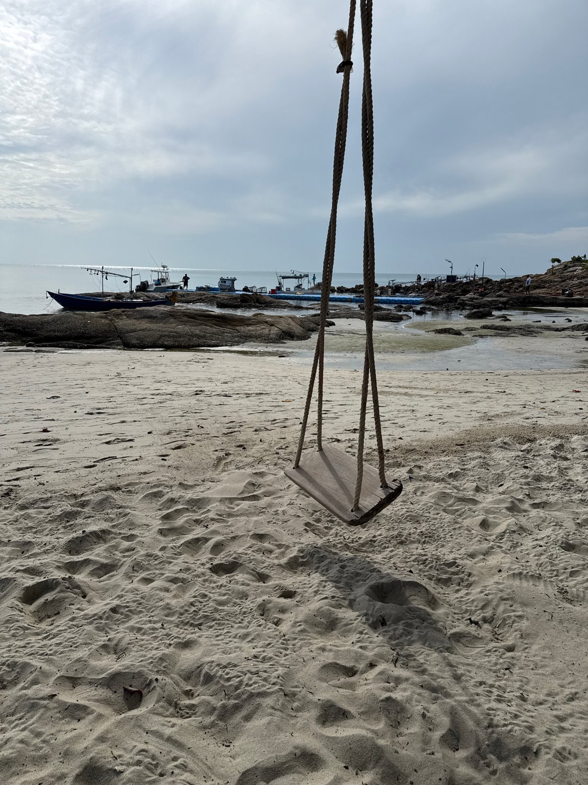 Weathered swing and clear shallows at a Ko Samui rocky beach