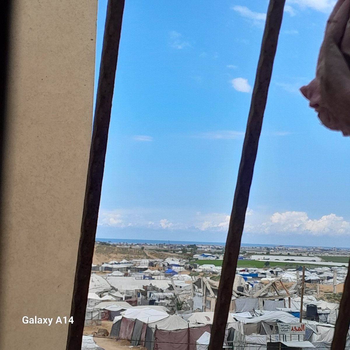 Witnesses document refugee camp scenes from elevated urban positions