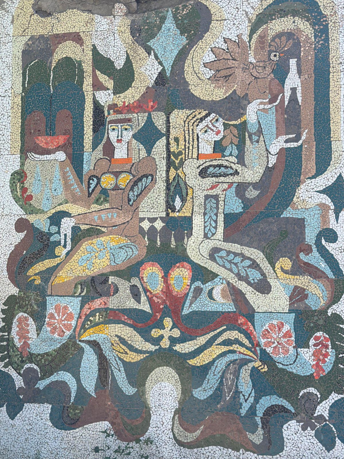Surreal mosaic mural on a weathered building in Surami, Georgia